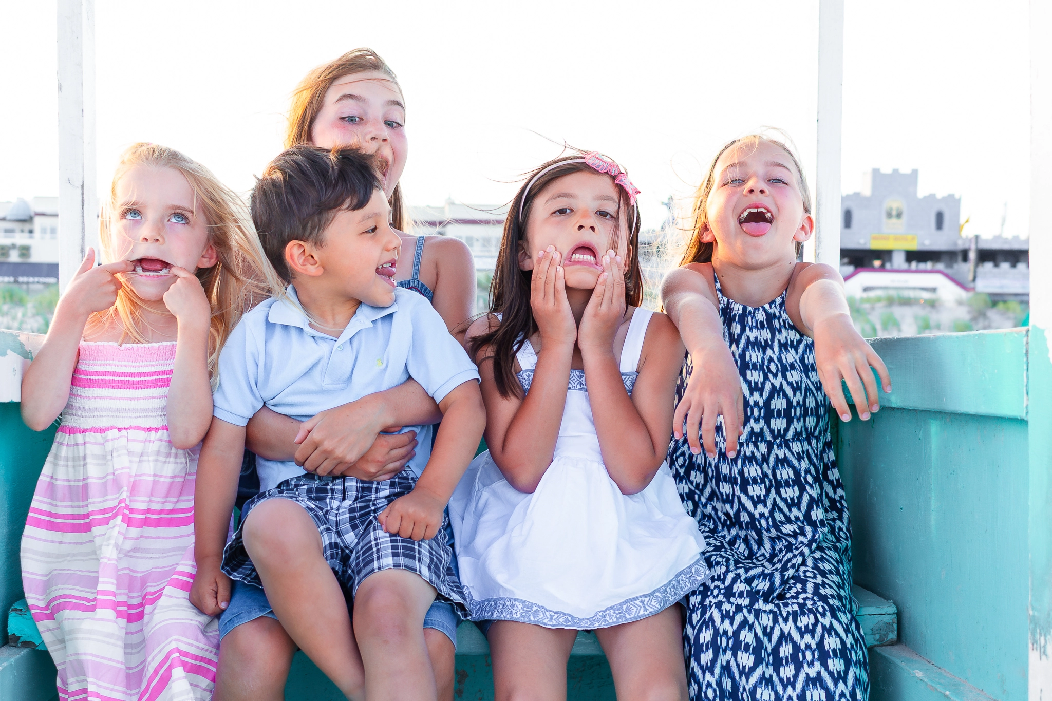 young children smiling in a lifeguard stand on the beach