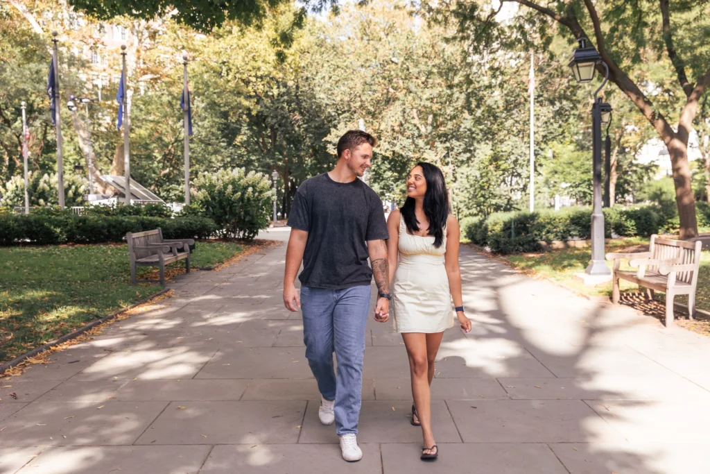 Happy couple smiling and holding hands during an engagement session at Washington Square Park in Philadelphia, PA.